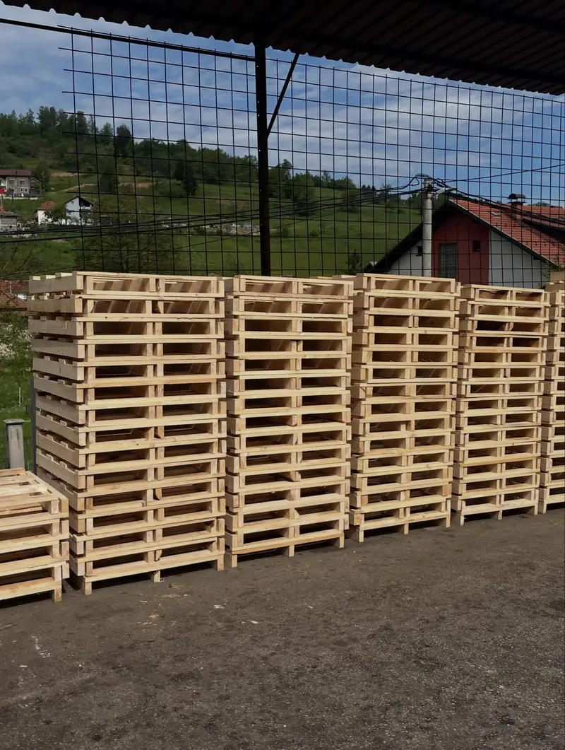 Složaji paleta ispred ograde, brda u pozadini